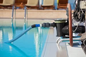 A Portable Black Pool Cleaning Pump System With A Blue Suction Hose Submerged In A Clear Outdoor Swimming Pool At A Resort For A Variable Speed Pool Pumps In Ocala And In The Villages.