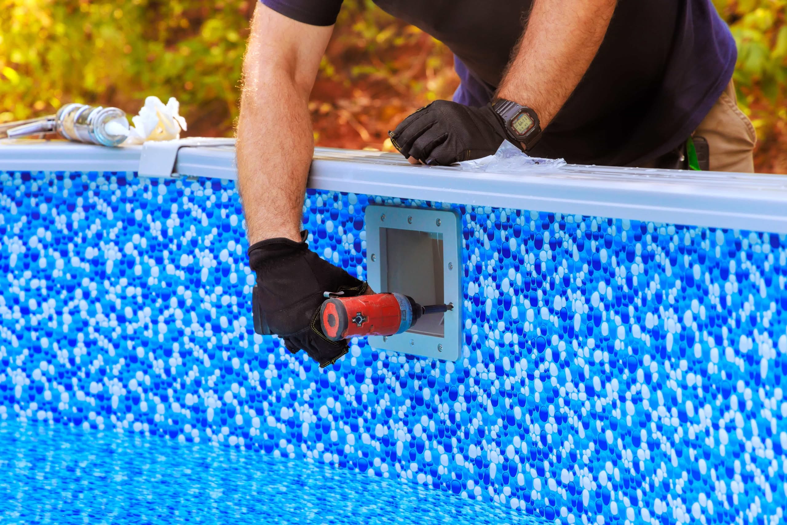 LED Pool Light Installation and Repair Ocala: The Ultimate Best Success 1 A Close-Up Of A Pool Technician'S Hands In Black Gloves Using A Power Drill To Secure A Skimmer Faceplate Onto A Blue Mosaic-Patterned Vinyl Pool Liner.