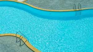 An Inviting, Winding Turquoise Swimming Pool With Sparkling Clear Water, Metal Ladders, And A Grey Patterned Stone Deck At A Resort For Otow Ocala Pool Remodeling &Amp; Resurfacing.