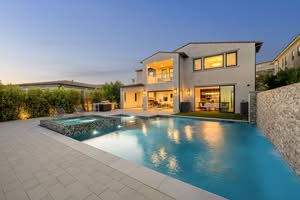 A Striking Twilight View Of A 2026 Custom Pool Trends At A Two-Story Hillside Mansion Featuring Integrated Warm Pool Lighting, An Infinity Edge Drop-Off, A Zero-Edge Spillover Spa, And A Concrete Patio Lounging Deck Overlooking The City In Los Angeles, California.