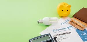 A Household Utility Budgeting Layout Featuring An Electricity Bill, Gas Bill, An Energy-Efficient Lightbulb, A Yellow Piggy Bank, Cash, Variable-Speed Pool Pumps Florida And A Calculator Over A Solid Green Background In Dallas, Texas.
